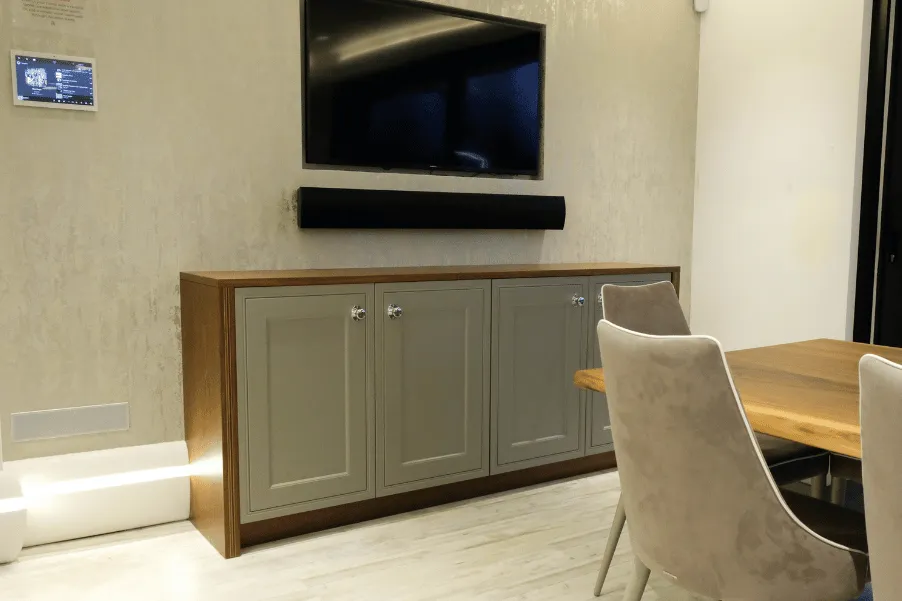 Media area with light green and wooden cabinets below TV mounted to wall