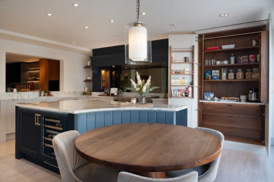 Island with curved booth and pantry cupboard with engraved drawers.