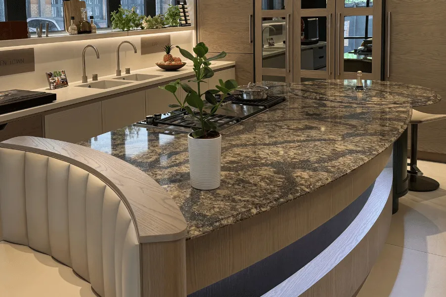 Booth seating and breakfast bar on ends of a curved kitchen island with veined worktops