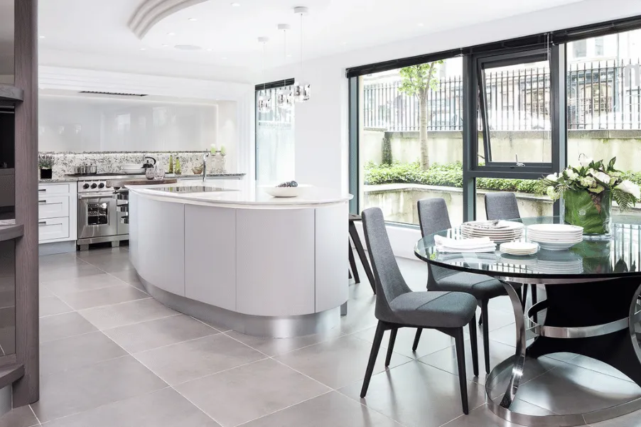 Inside of Kitchens International showroom with white curved kitchen island and glass dining table